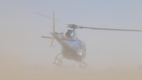 extremely dusty location with blue helicopter take off and car drives by