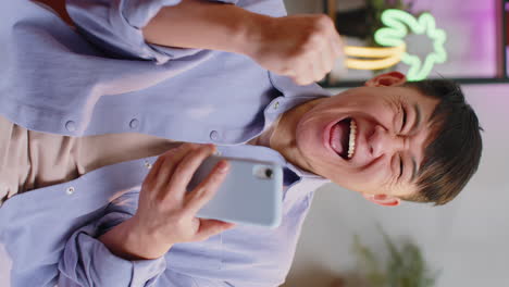 hombre asiático feliz en casa usar teléfono inteligente escribir navegación wow sí descubrió gran gran victoria celebrar