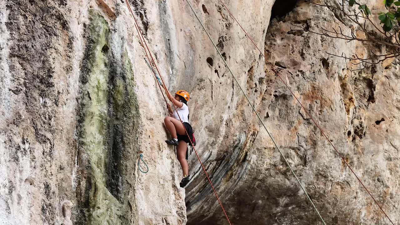 el escalador escala el acantilado con el equipo de apoyo debajo