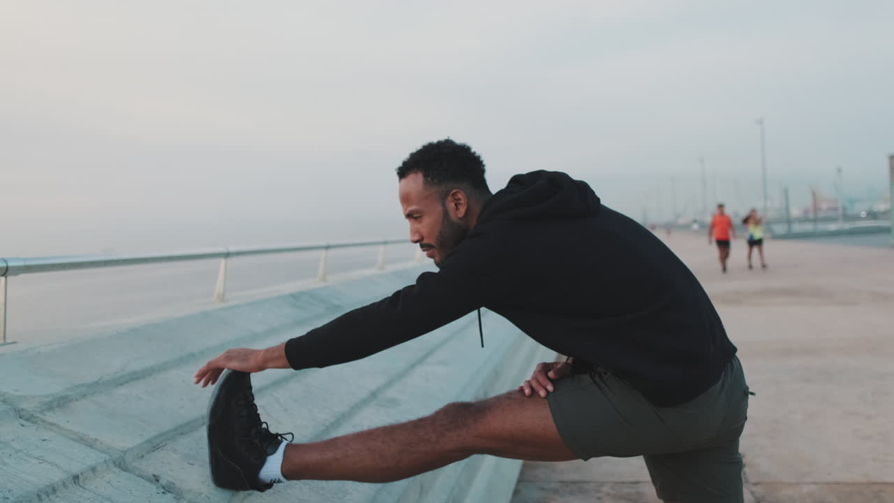 A man stretching on a road outdoors