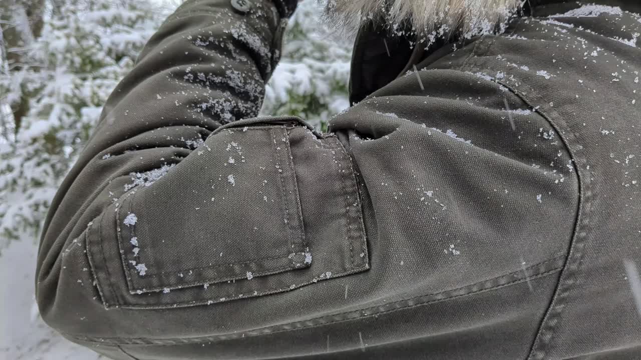hombre bebiendo café afuera en la naturaleza en un día de invierno mientras nieva