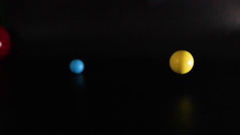 various balls and objects moving against a dark background