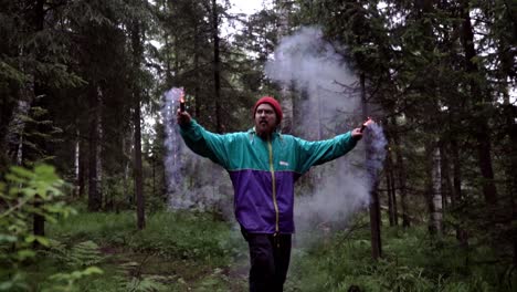 man playing with smoke bombs in a forest