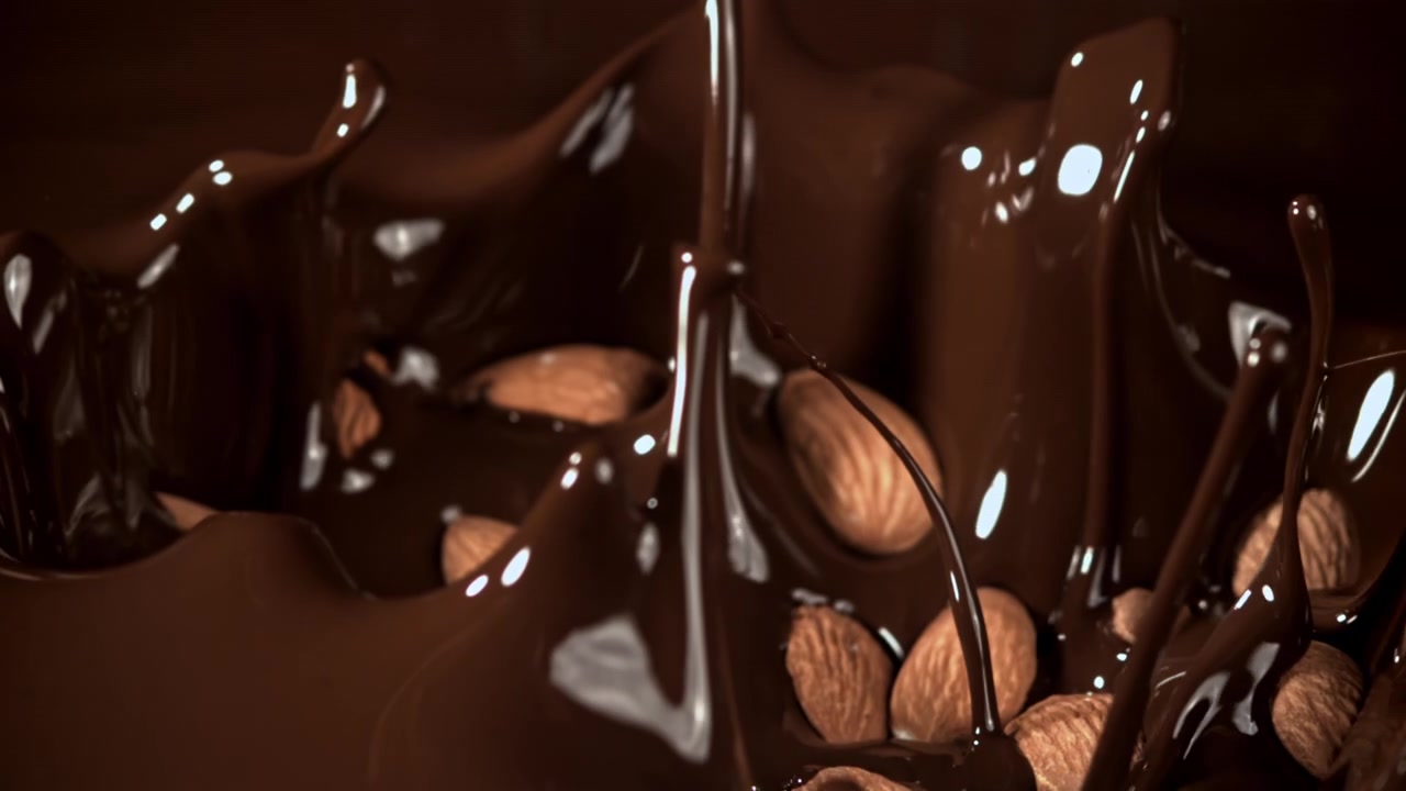 Mandorle che cadono nel cioccolato fuso al rallentatore
