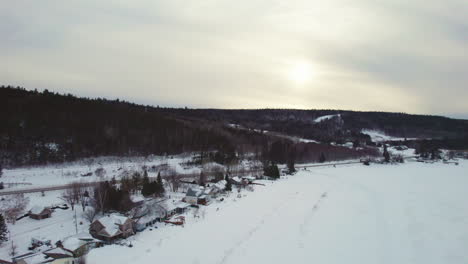 Fliegende-Drohne-über-Häusern-Und-Einem-Wald-Im-Winter-In-Kanada