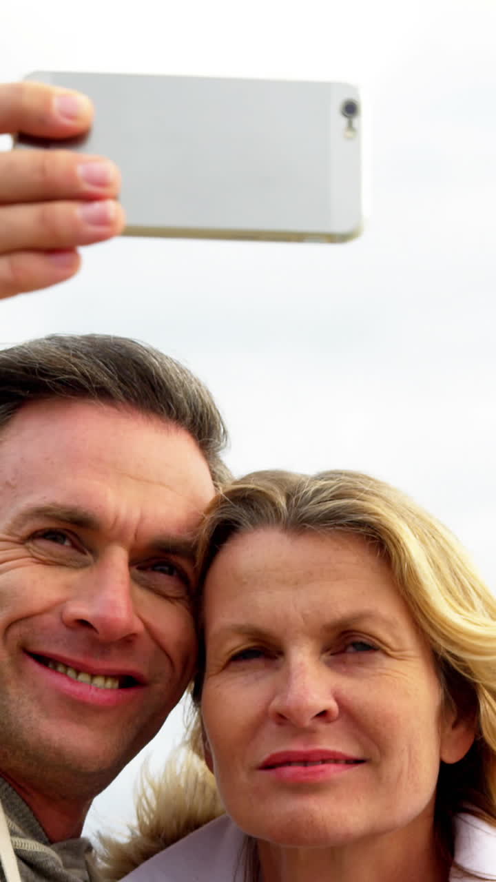 Keski-ikäinen pariskunta ottaa selfien matkapuhelimella