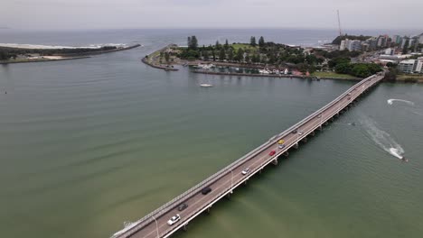 vehicles driving on head street bridge over coolongolook river with boats cruising. forster, new south wales, australia. aerial static shot