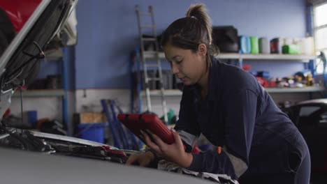 mecánica usando una tableta digital e inspeccionando el automóvil en una estación de servicio de automóviles