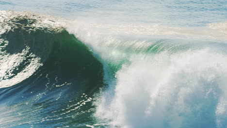 slow motion view of surfer sitting on boards as stunning green wave barrels and crashes across open ocean waters