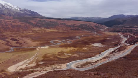 Sichuan-Genyen-holy-mountain-with-winding-road-and-meandering-river-below-snowy-peaks