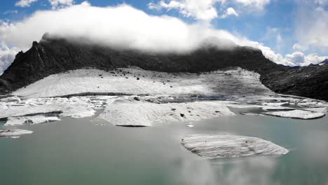 aerial flyover above an iceberg in a melting glacier lake in remote parts of the swiss alps on a sunny day