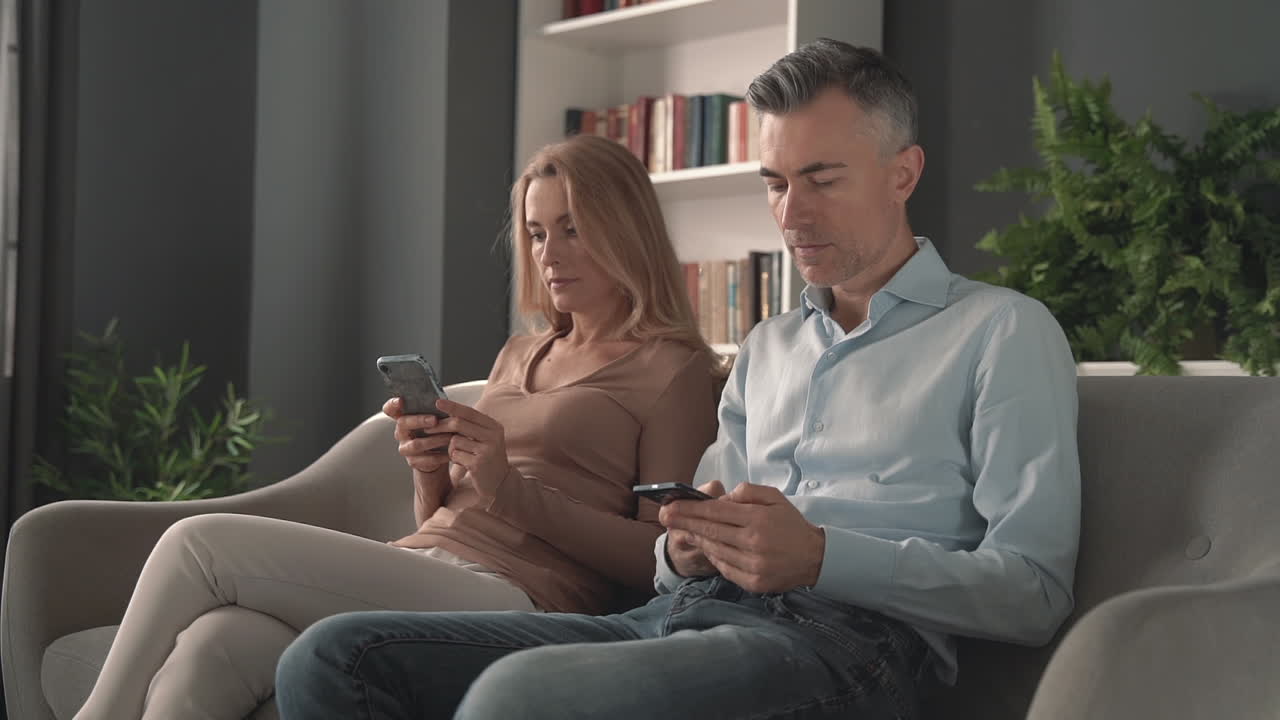 Phone and work addiction. Mature male and female using a smartphone.