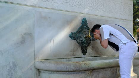 Hombre-Bebiendo-Agua-De-La-Fuente-Alemana-Del-Parque-Sultanahmet-En-Estambul