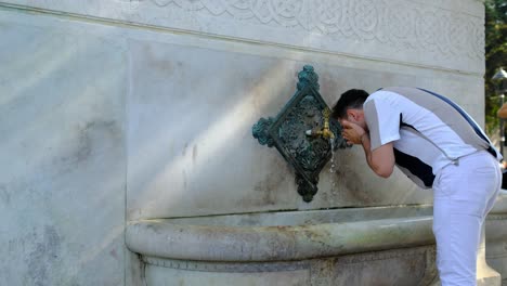 hombre bebiendo agua de la fuente alemana del parque sultanahmet de estambul
