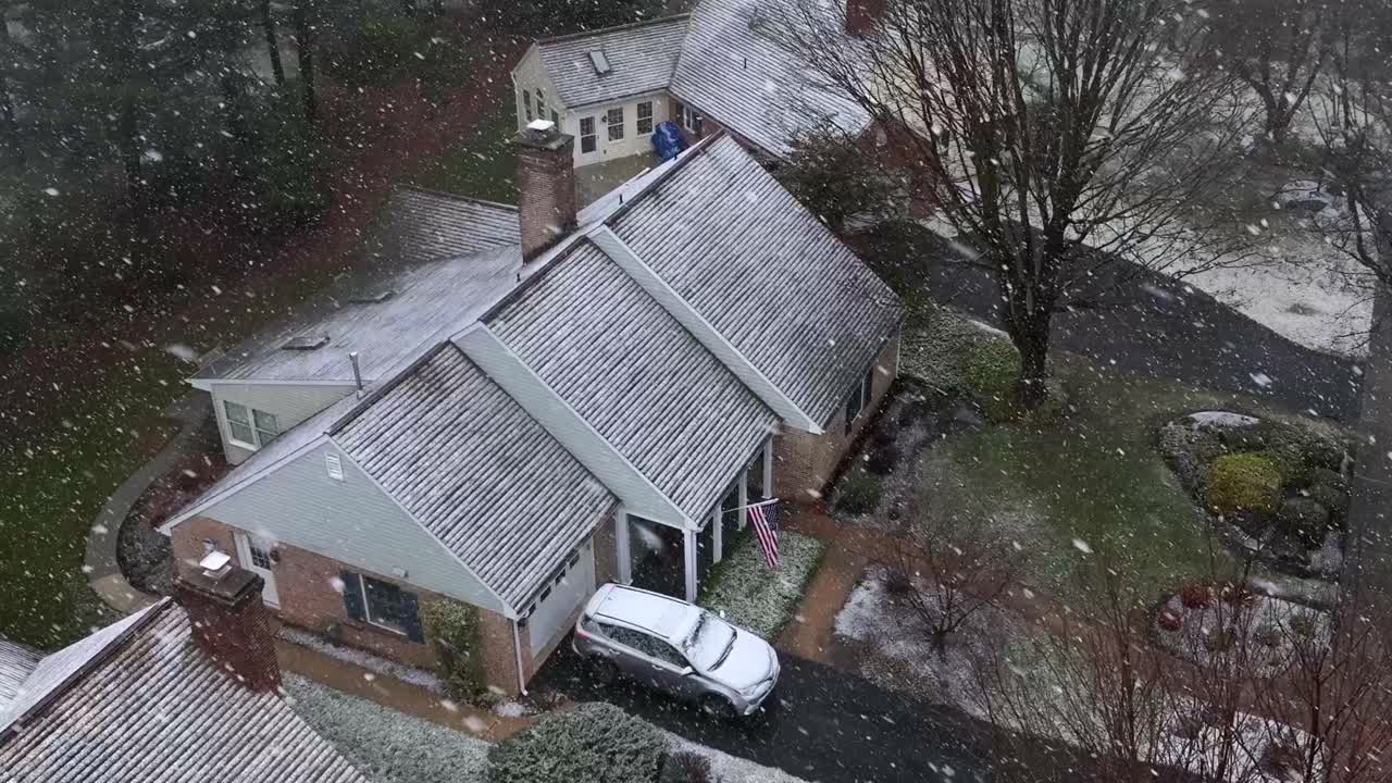 Aerial top down establishing shot of American home during winter snowstorm