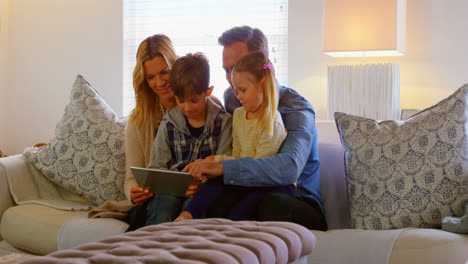 Front-view-of-young-Caucasian-family-using-digital-tablet-in-living-room-of-comfortable-home-4k