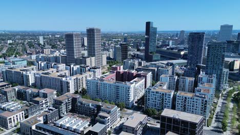 Aerial-view-flying-over-Stratford-London-downtown-district-skyscraper-cityscape-blocks-under-blue-sky