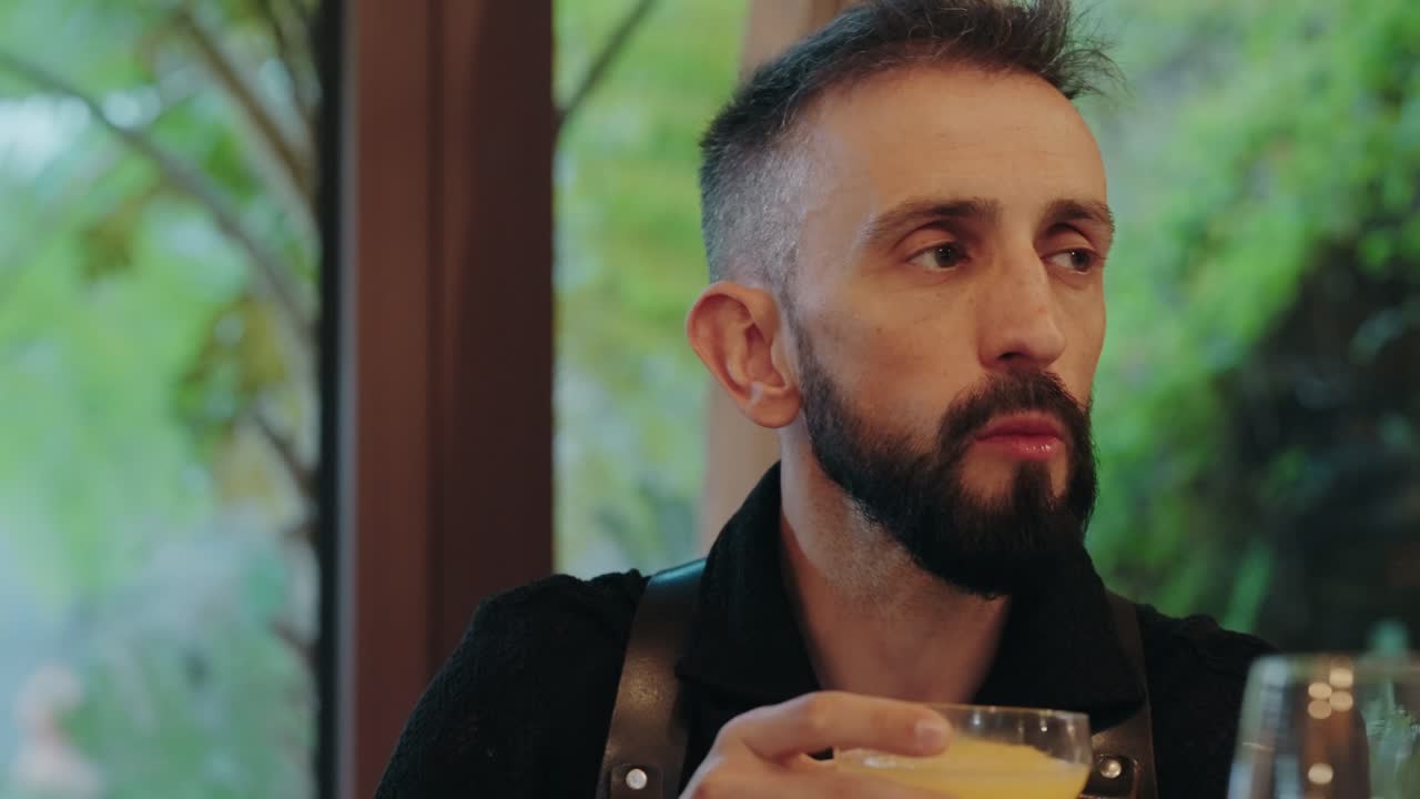 closeup of man sipping orange drink from glass in cozy restaurant atmosphere