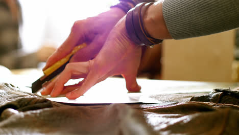 mid-section of craftswoman cutting leather