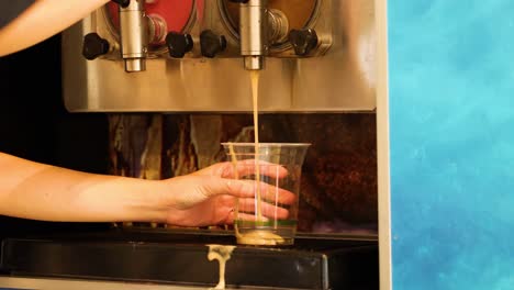 person filling cup with slushy drink