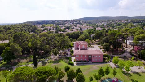 aerial view of a park with a red-roofed building and lush trees