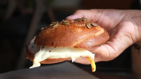 hand holding a delicious breakfast bagel sandwich