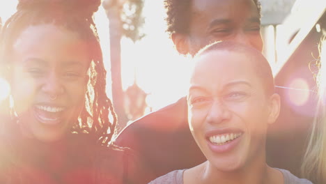 portrait of group of multi-cultural friends outdoors against flaring sun