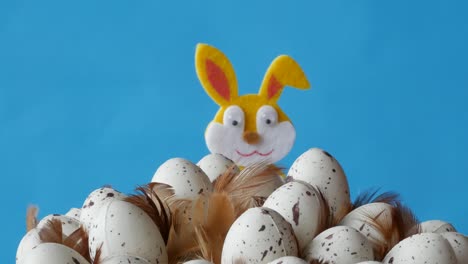 el conejo de pascua se esconde detrás de los huevos sobre un fondo azul.