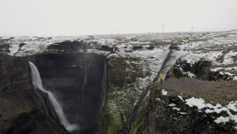 antena: una persona con chaqueta amarilla mirando la cascada granni en islandia