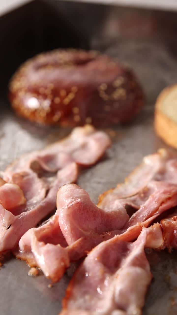 Pancetta sfrigolante e pane che cuociono su una piastra calda