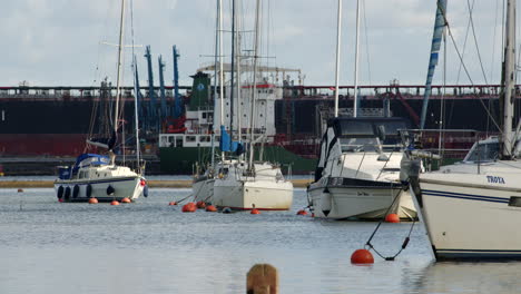 sailboat-moored-at-Ashlett-sailing-club-wave-tanker-in-background-at-Ashlett-creek-in-the-Solent,-Southampton