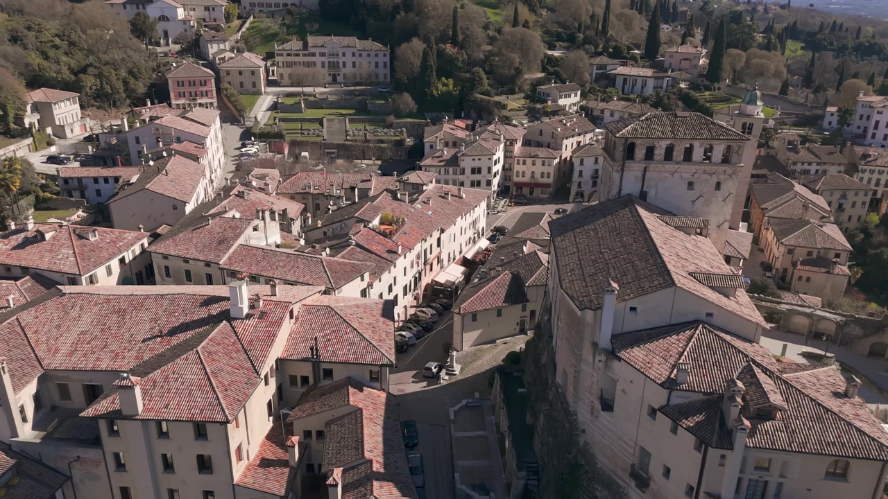 Vista aerea che si libra sui tetti e le stradine della storica città di Asolo sotto la luce del sole