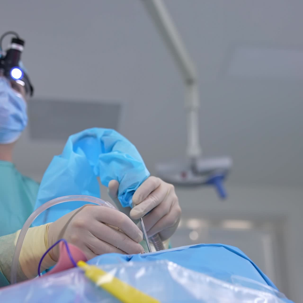 Surgical process in the operating room. Doctor and assistant perform a microsurgery to a patient's face using medical instruments