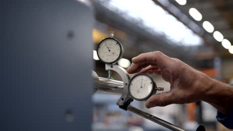 mechanic finalizing the adjustment of a measuring instrument in a polished metal bar