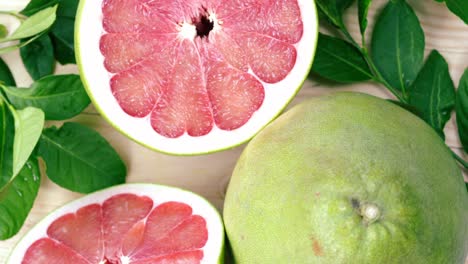 top view rotate red pomelo fruit with leaves on wooden table in garden, red pomelo fruit with leaves in wooden background 4k resolution.