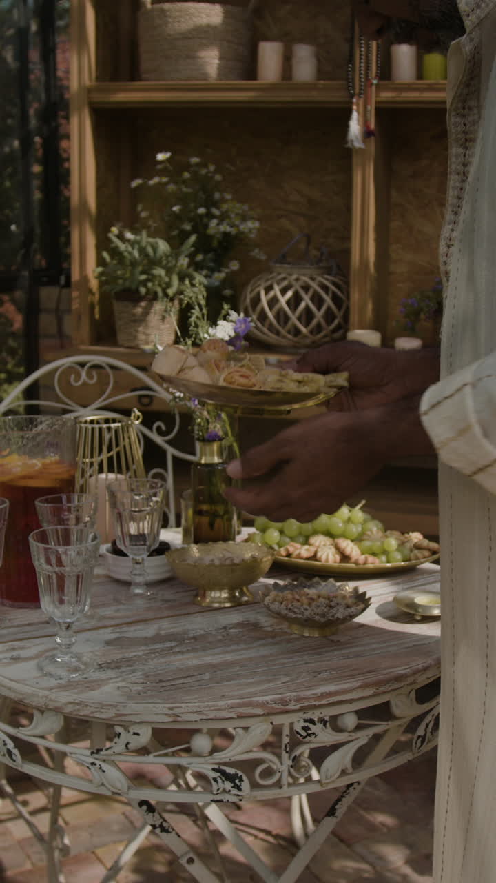 Man setting an outdoor table with food and drinks for a garden gathering