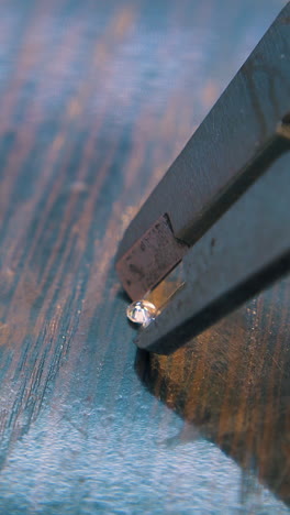 cu shot: skilled jeweler measures shining diamonds with sliding ruler on dark wooden table in workshop closeup