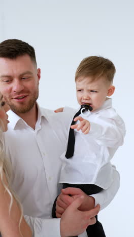 father and son wearing white shirts. little baby starting to cry. parents soothing their child. vertical video.