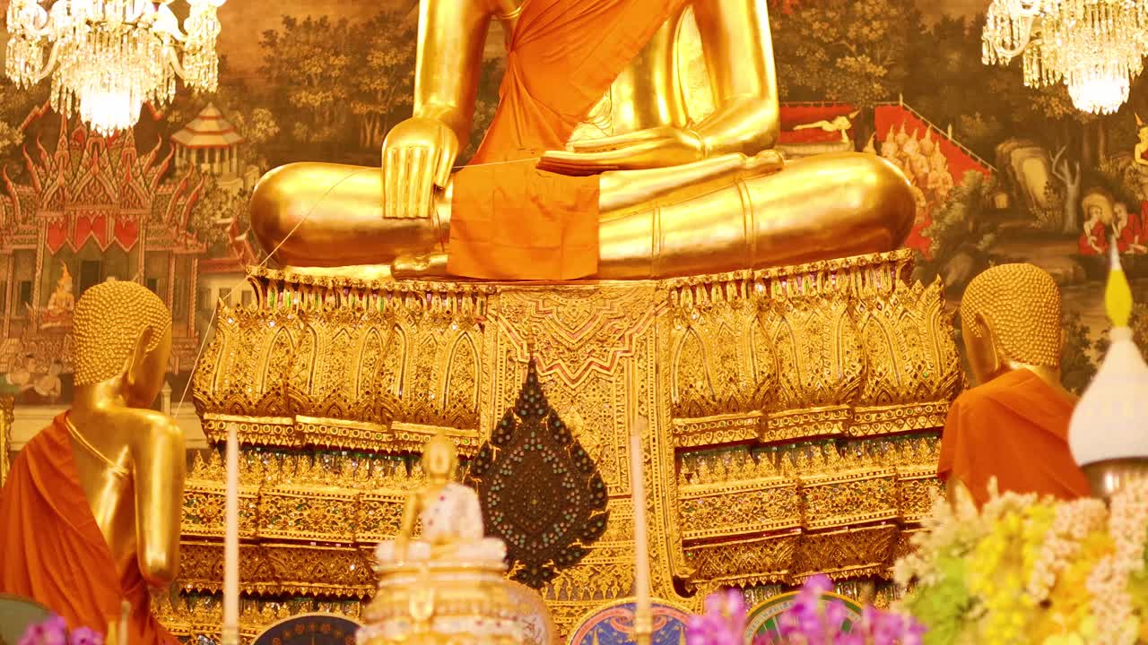 A serene golden Buddha statue surrounded by vibrant flowers and ornate decor in Wat Arun, captured with warm lighting