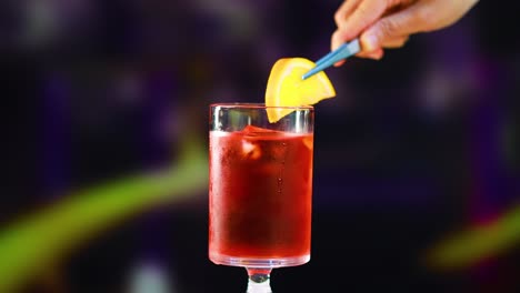 a negroni cocktail is garnished with an orange slice against a blurred background, highlighting vibrant colors and a relaxed mood