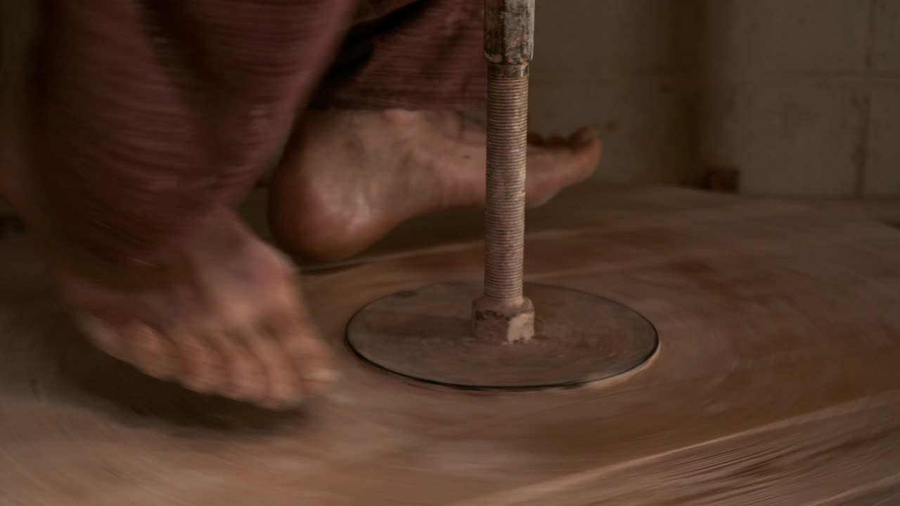 el alfarero gira la rueda de madera de la rueda del alfarero con sus pies