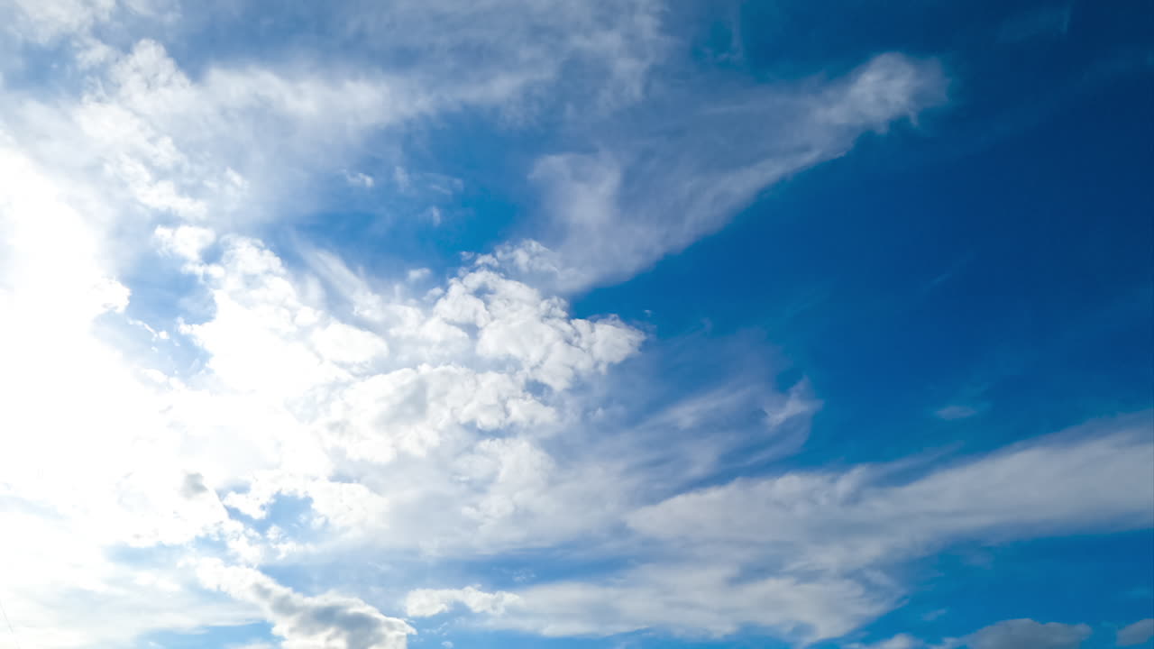 Soft light white clouds moving in different directions. Spindrift clouds lit with bright sun. Timelapse.