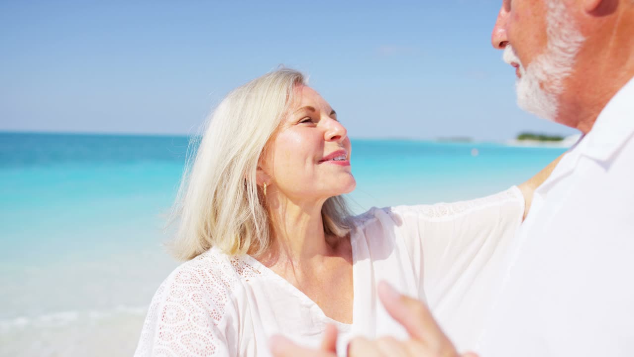 зрелая кавказская пара танцует на тропическом пляже