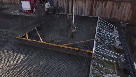 Aerial-view-of-construction-workers-laying-wet-cement-using-automatic-pump