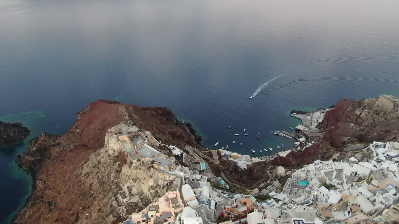 vista de avión no tripulado en grecia volando sobre santorini con la ciudad de oia casas blancas y techos azules en un acantilado junto al mar mediterráneo al amanecer