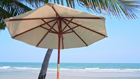 Isolated-Parasol-under-Palm-Tree-Leaves-on-Tropical-Beach