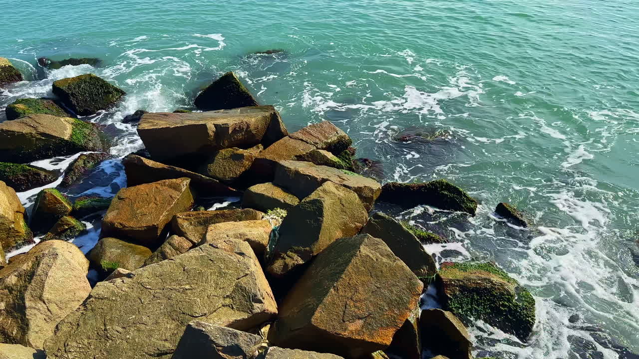 Solbeskinnede klipper ved det turkise hav en rolig eftermiddag på stranden