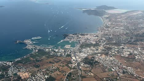 elevated aerial spinning view of ibiza city, harbor and airport shot from an airplane cockpit at 2000m high