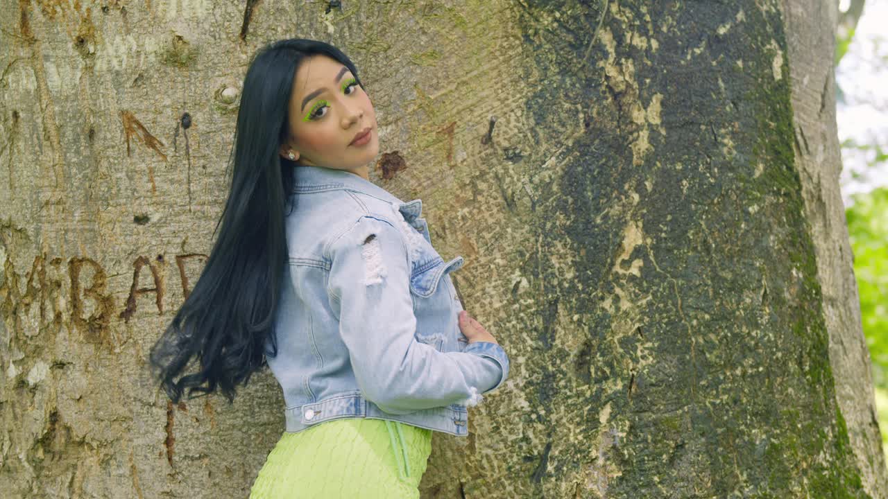 chica latina con una chaqueta se vuelve y revela su vestido verde corto