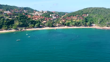 drone taking footage from green cliff on the ocean shore in buzios, brazil